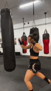 a woman is kicking a punching bag in a gym .
