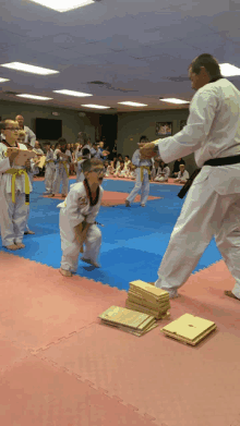 a group of kids are practicing martial arts with a man in a white uniform