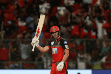 a cricket player holds up a bat that says mrf on the front