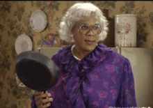 a woman in a purple shirt is holding a pan