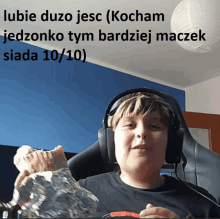 a boy wearing headphones holds a piece of bread in front of a sign that says lubie duzo jesc kocham