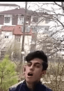 a young man is making a funny face in front of a building .