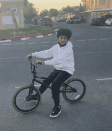 a young boy is riding a bike on a street that has a sign that says ' eastern ' on it