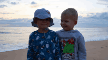 two young boys standing on a beach with one wearing a hoodie that says avengers