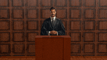 a man in a judge 's robe stands behind a podium