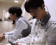 a man wearing a microphone sits next to another man wearing a microphone