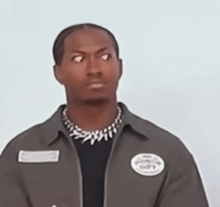 a man wearing a black shirt and a grey jacket has a patch on his jacket that says ' gangs ' on it