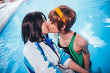 two women kissing in a pool with one wearing a speedo