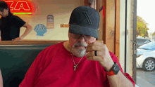 a man wearing a hat with the letter x on it looks at his phone