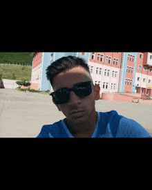 a young man wearing sunglasses is taking a picture of himself in front of a building