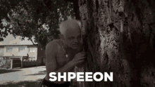 a man without a shirt is peeking out from behind a tree and says `` shpeeon '' .