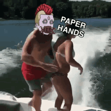 a man and a woman are on a boat and the man has a mask on that says paper hands