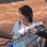 a woman in a blue dress is being held by a person with chinese writing on their face