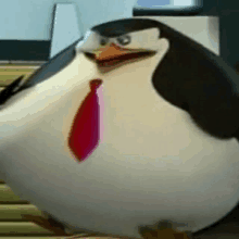 a penguin wearing a red tie is standing on a table .