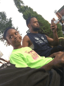 a man wearing a shirt that says eagles on it sits next to a girl in a neon green shirt