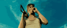 a man in a tank top and goggles is holding a gun .