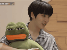 a man is holding a stuffed frog with a yellow beak