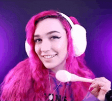 a woman with pink hair is wearing headphones and holding a spoon in her hand .