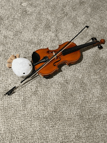 a violin and bow on a carpet with a stuffed animal