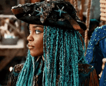 a woman with blue braids is wearing a pirate hat and looking to the side .