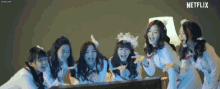 a group of girls are standing around a piano laughing and pointing at the camera .