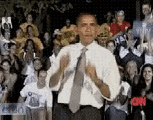 a man in a white shirt and tie stands in front of a crowd with cnn written on the bottom right corner