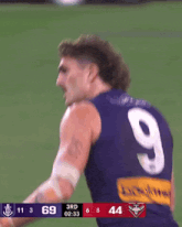 a man wearing a number 9 jersey stands in front of a scoreboard