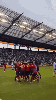 a group of soccer players huddle on a field with a scoreboard behind them that says ' rtl ' on it