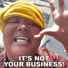 a woman wearing a yellow head scarf is saying it 's not your business