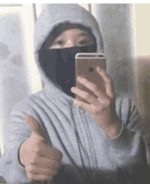 a person in a hoodie taking a selfie with their phone