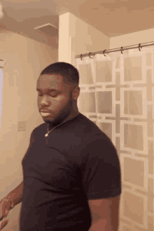 a man in a black shirt stands in front of a shower curtain with squares on it