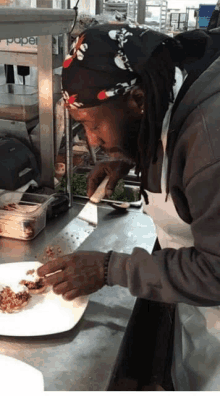 a man wearing a bandana with skulls and crossbones on it prepares food