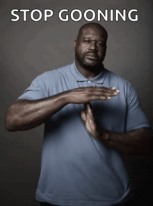 a man in a blue shirt is making a stop goon sign