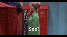 a woman in a green shirt is standing in front of red lockers with the words see written below her