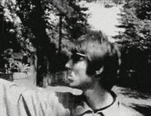 a black and white photo of a man wearing sunglasses and a shirt .