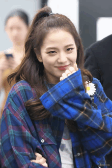 a girl wearing a blue plaid shirt with a daisy on her shoulder