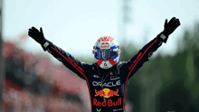 a man wearing a red bull jacket and helmet celebrates his victory