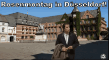 a man in a suit stands in front of a large building with the words rosenmontag in dusseldorf written above him