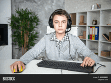 a boy wearing headphones and a microphone is using a computer