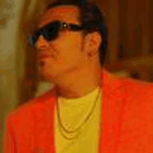 a man wearing an orange jacket and sunglasses is looking to the side .