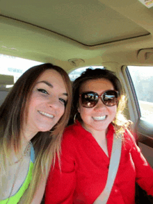 two women are sitting in a car and smiling for a picture