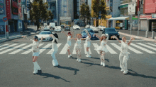 a group of women are dancing on a crosswalk in front of a sign that says ' a ' on it