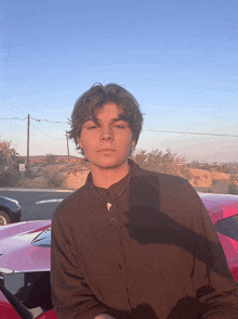 a young man stands in front of a pink car