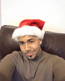 a man wearing a santa hat is sitting on a leather couch