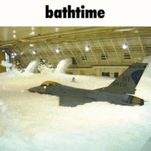 a fighter jet is covered in foam in a hangar with the words bathtime above it