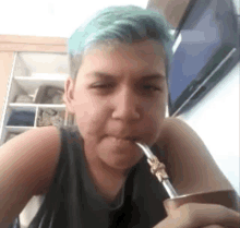 a person with blue hair is drinking from a cup with a straw