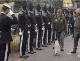 a woman walking a penguin in front of a line of soldiers with the letters a and b on their uniforms