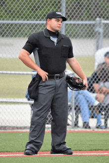 a baseball referee stands on the field holding a catcher 's mitt