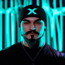 a man with a beard wears a black beanie with an x on it