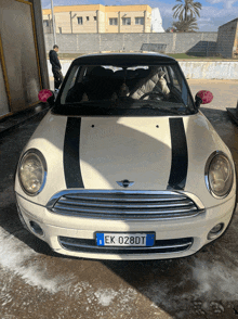 a white mini cooper with a license plate that says ek 028dt